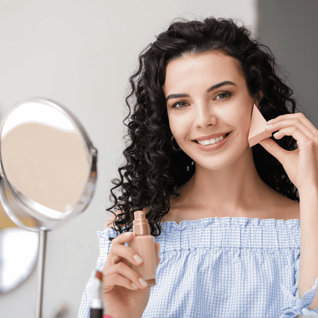 Mulher jovem aplicando base com esponja.